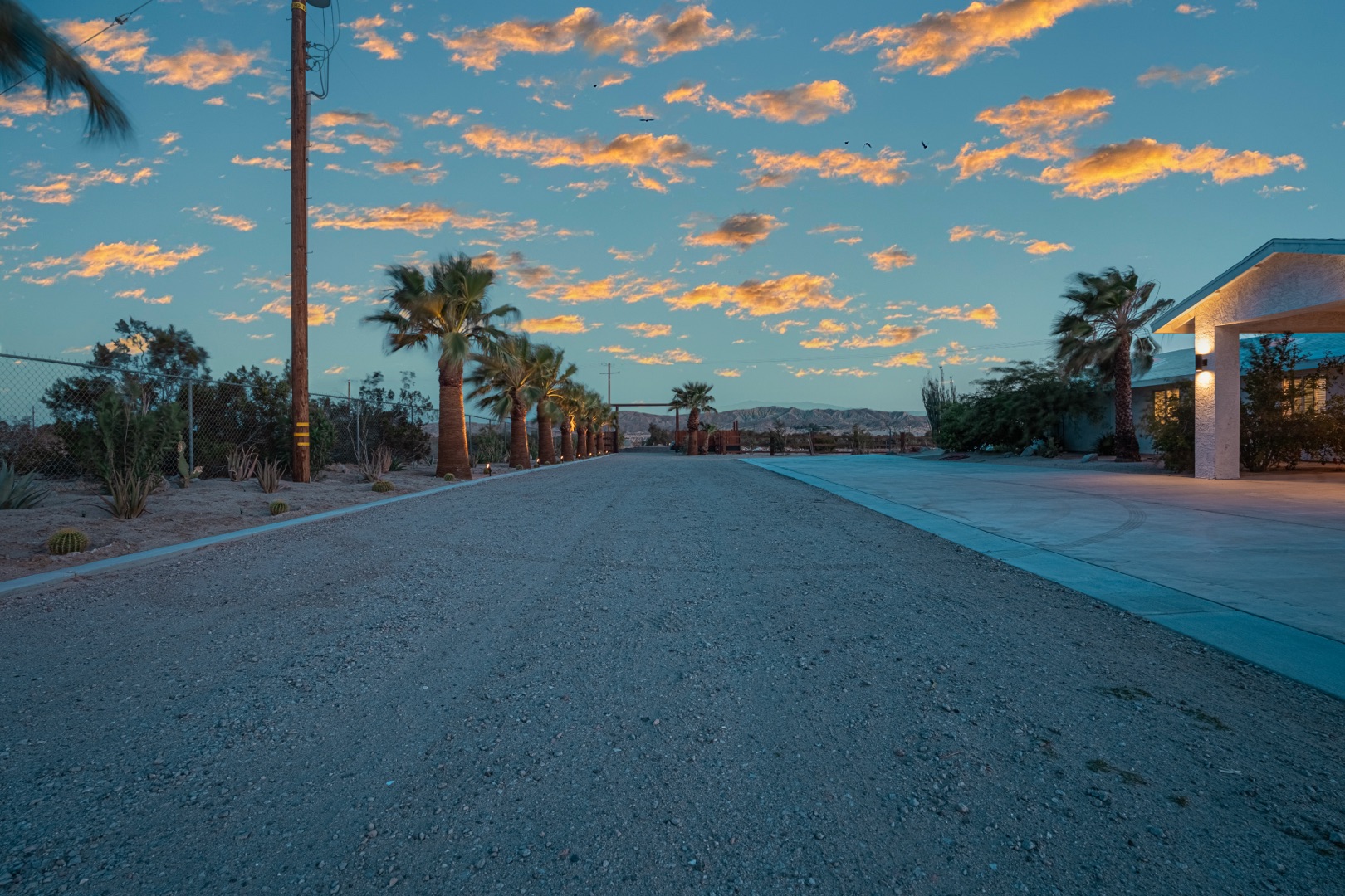 A dry wedding venue rental property in Sky Valley with a glowing pool, private desert landscape, and Joshua Tree boulders at golden hour