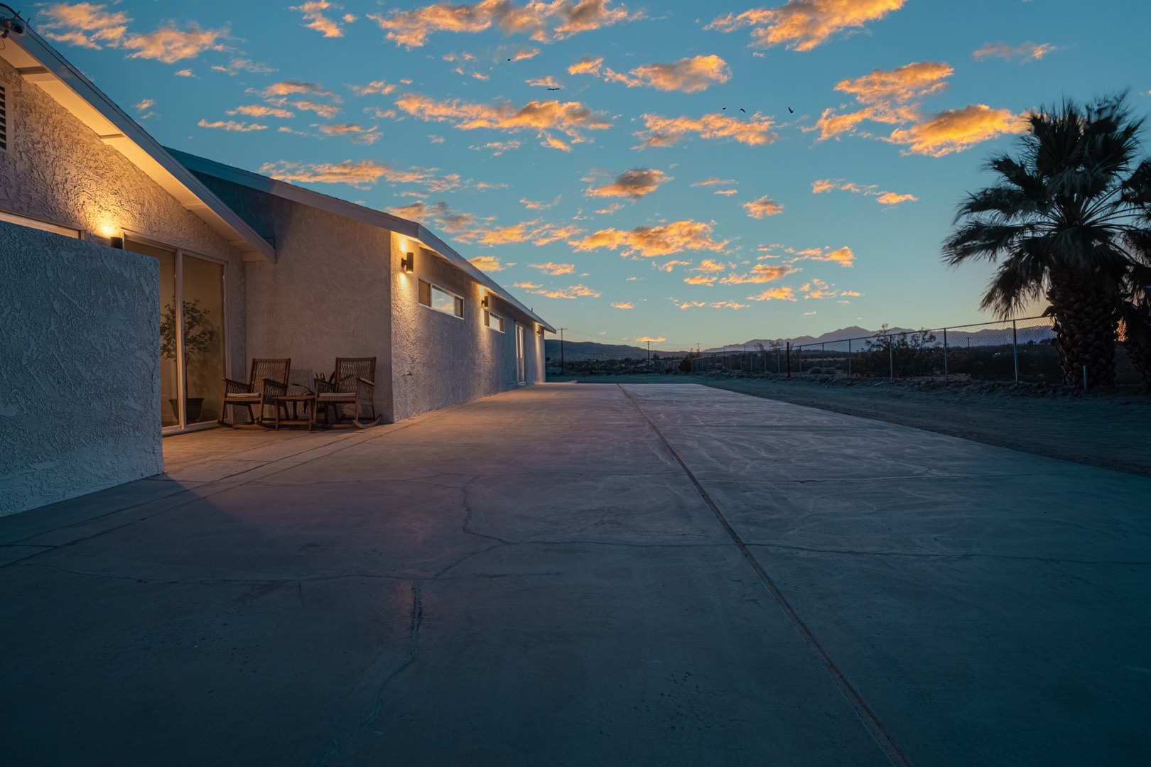 A model in an editorial gown poses on a private desert estate during a fashion shoot location desert, warm golden light illuminating the Mojave landscape behind her.